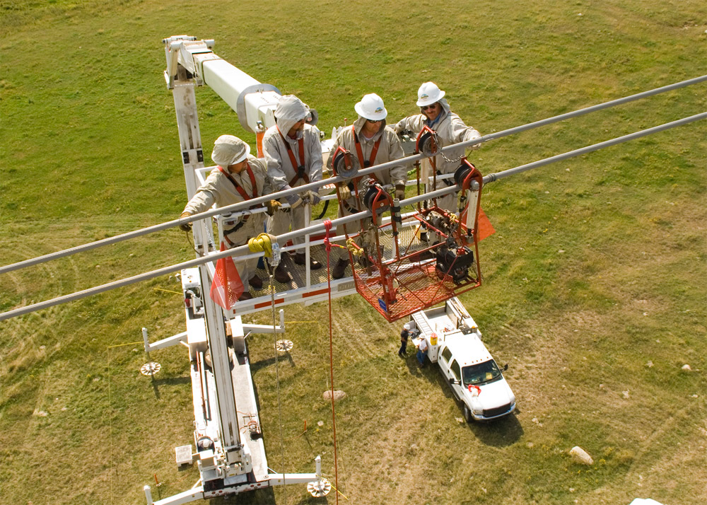 Basin Electric Power Cooperative Linemen work on a high-voltage transmission line from a bucket truck.