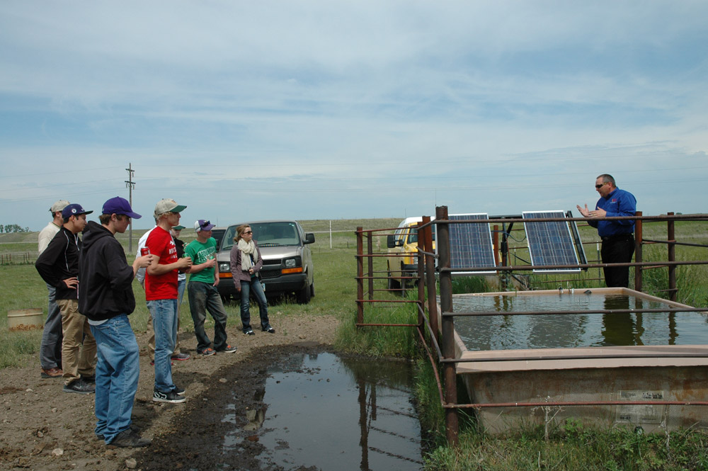 Tom Jesperson of Verendrye Electric explains to students that solar energy is used to pump water for cattle to drink