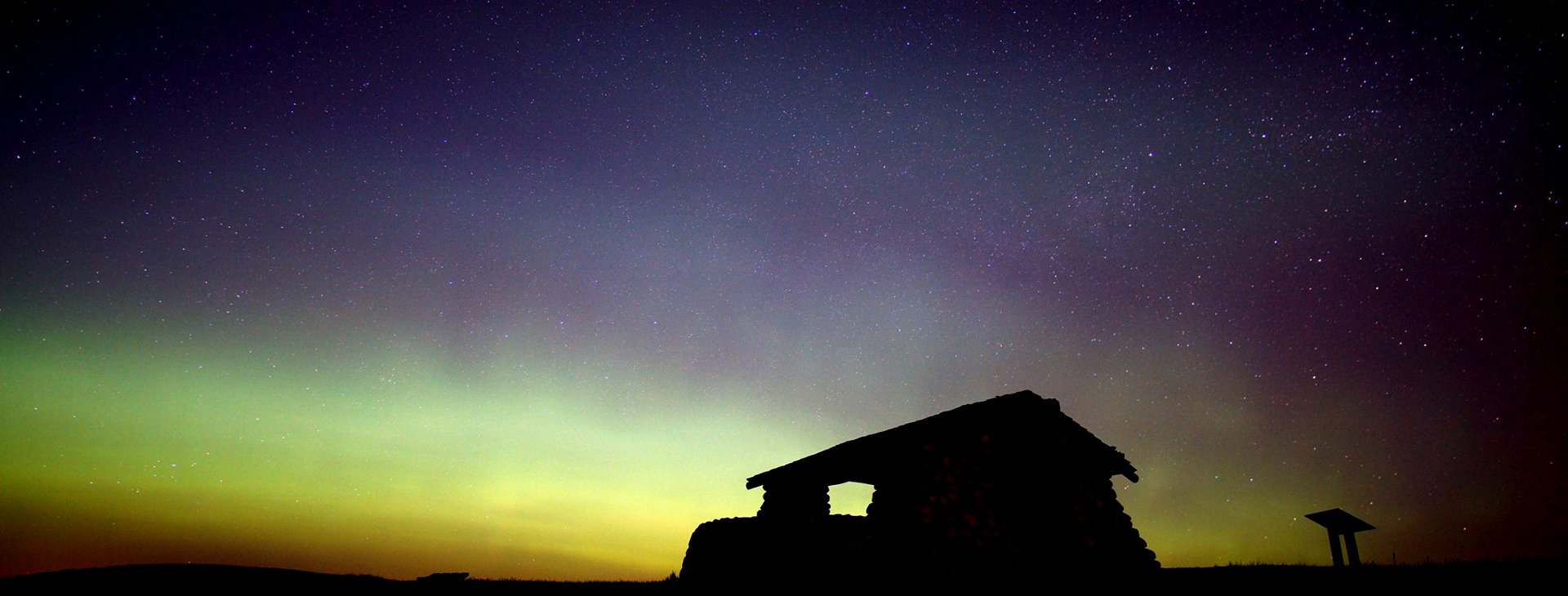 Image is of Double Ditch State Historic Site at night with the auroras overhead.